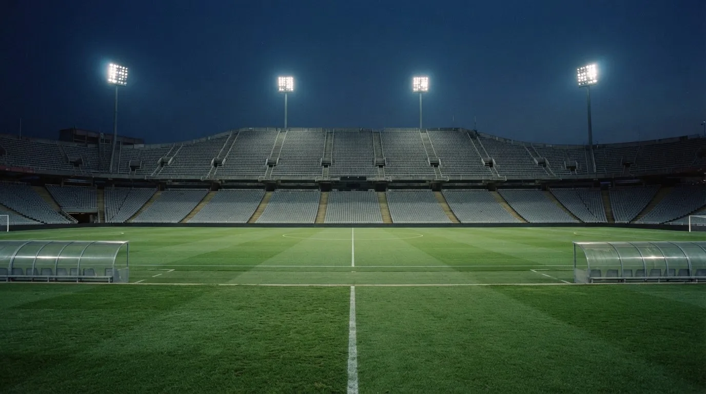 Een leeg voetbalstadion met lichtmasten bij schemering
