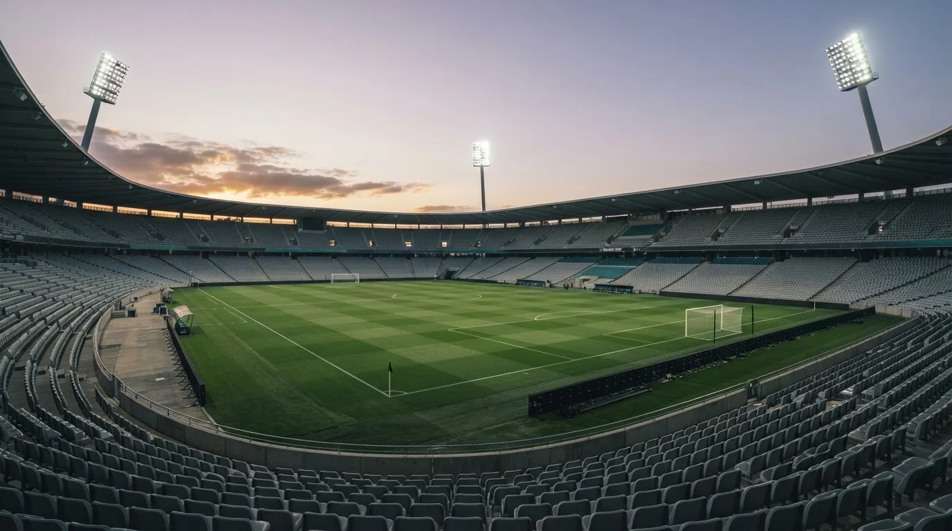 Een leeg voetbalstadion met lichtmasten bij schemering