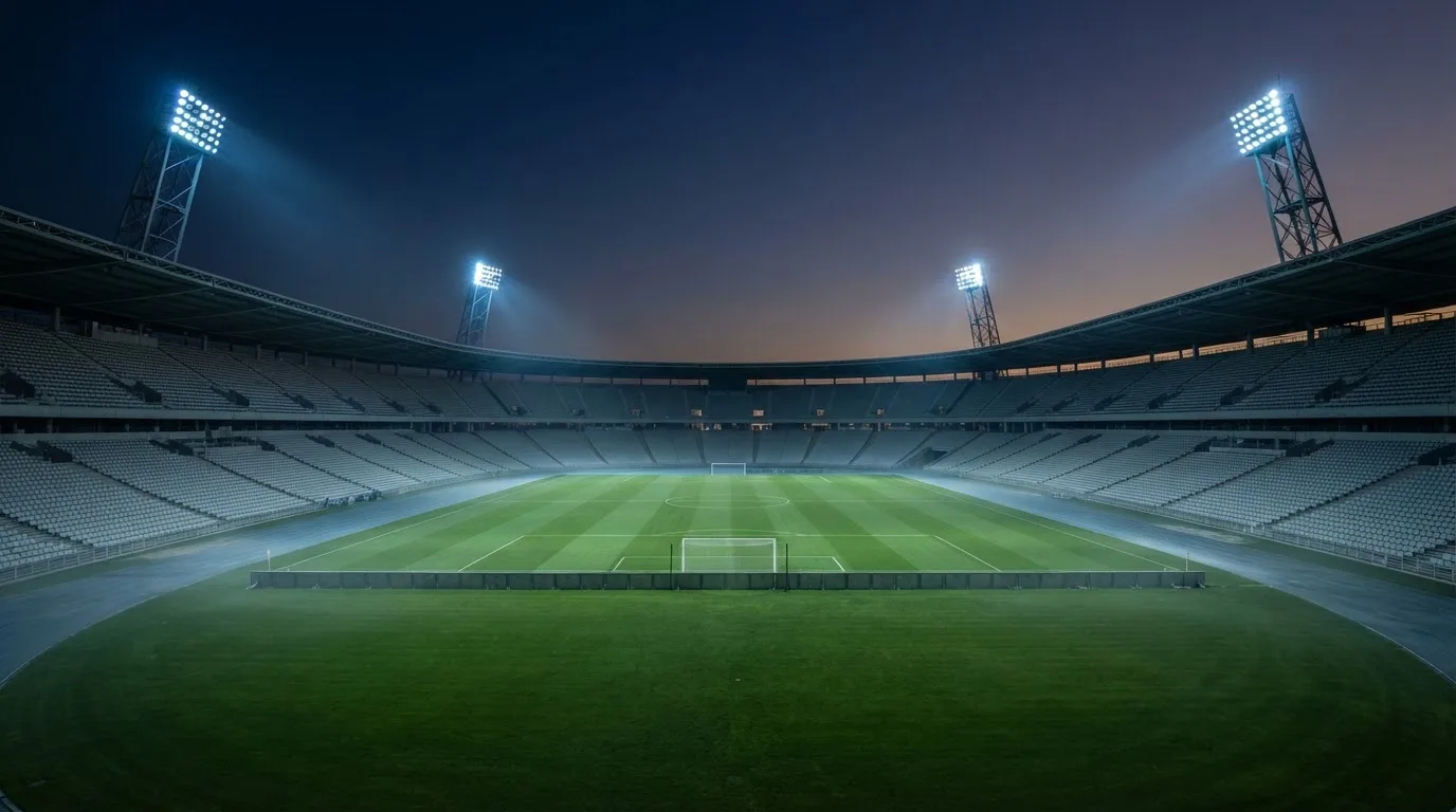 Een leeg voetbalstadion met lichtmasten bij schemering