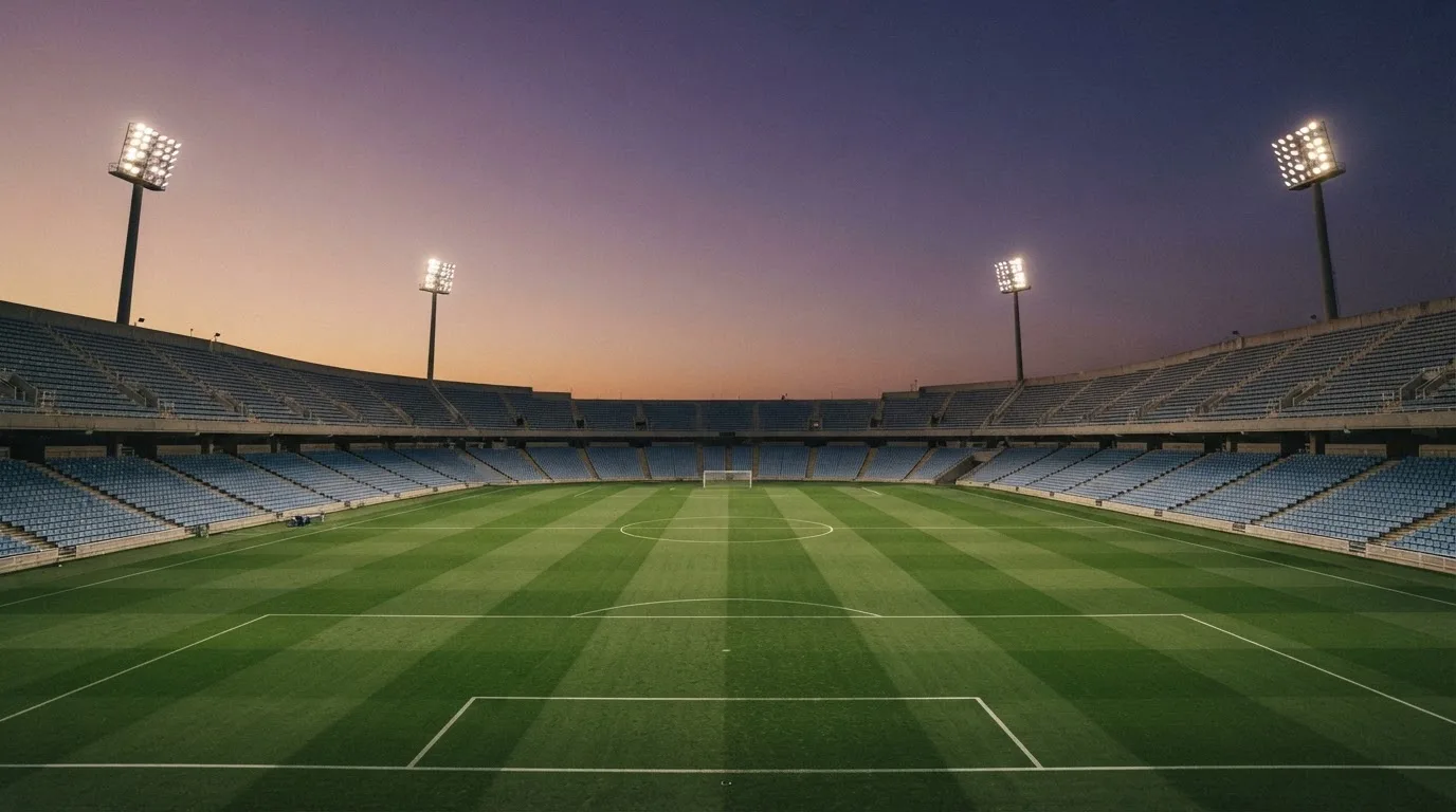 Een leeg voetbalstadion met lichtmasten bij schemering