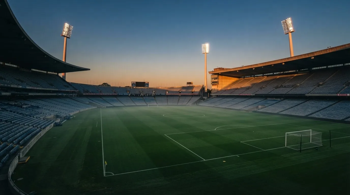 Een leeg voetbalstadion met lichtmasten bij schemering