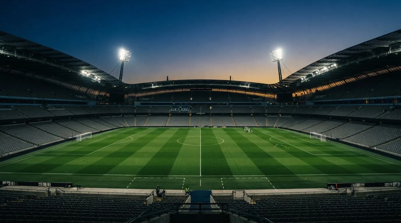 Een leeg voetbalstadion met lichtmasten bij schemering