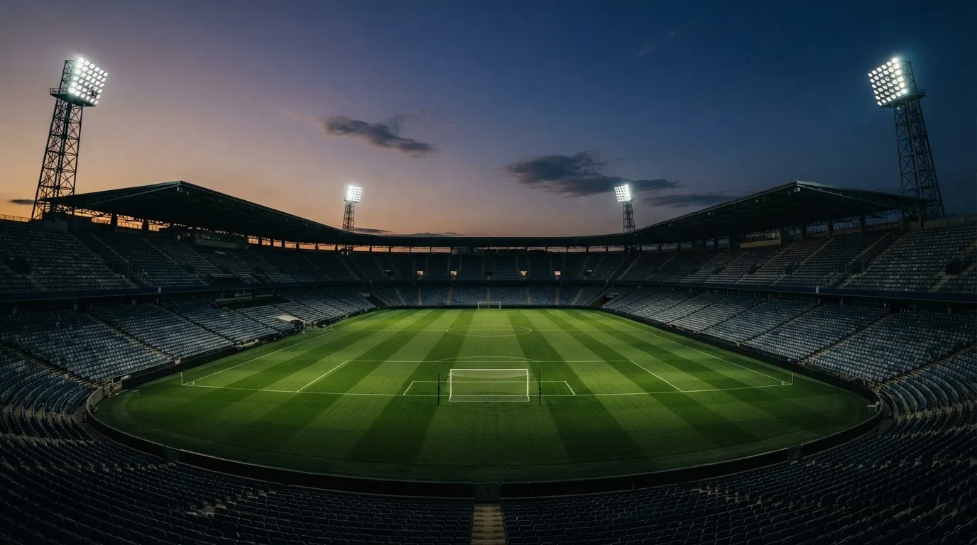 Een leeg voetbalstadion met lichtmasten bij schemering