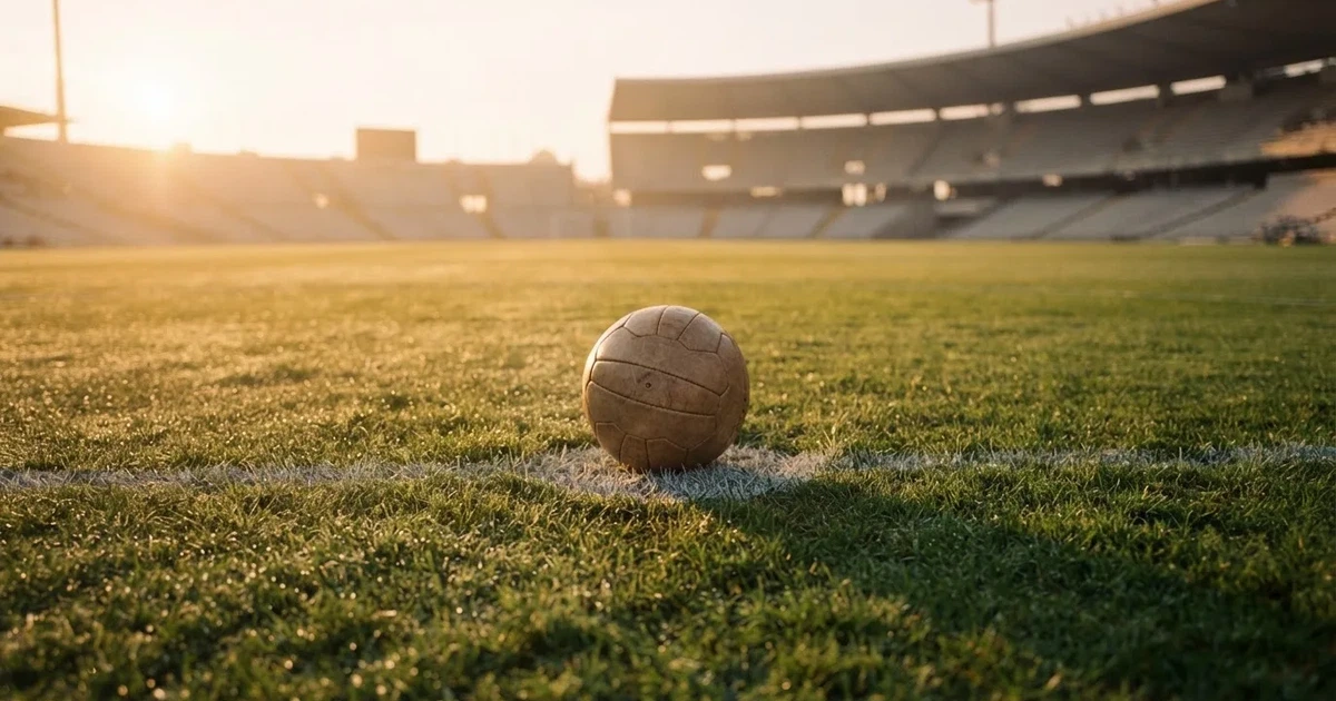 Een voetbal op de middenstip van een grasveld in het ochtendlicht