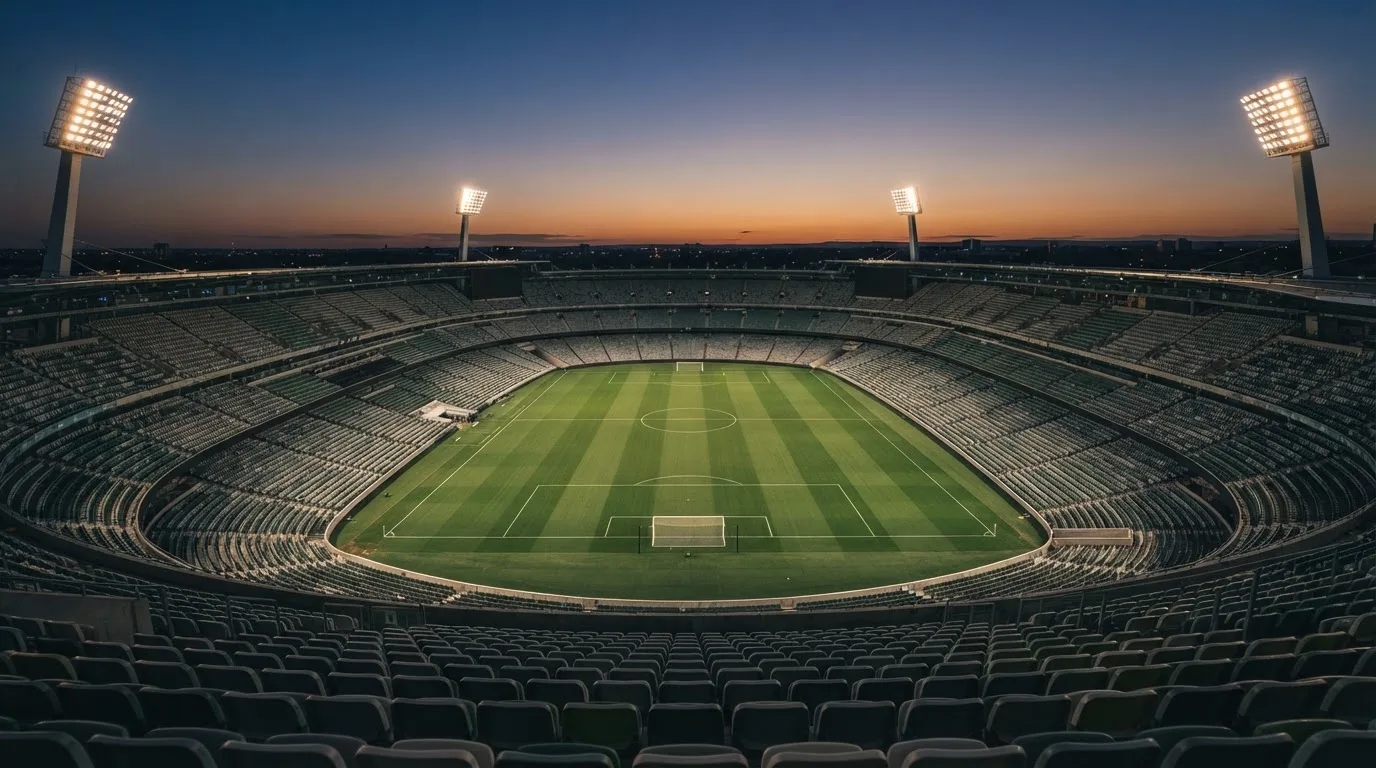 Een leeg voetbalstadion met lichtmasten bij schemering