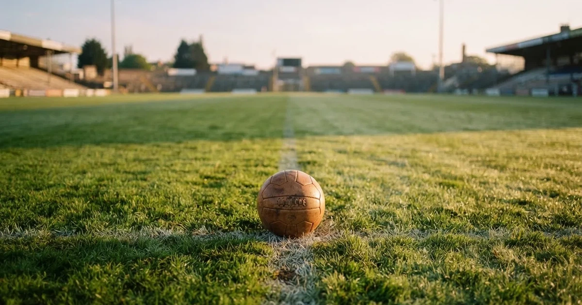 Een voetbal op de middenstip van een grasveld in het ochtendlicht