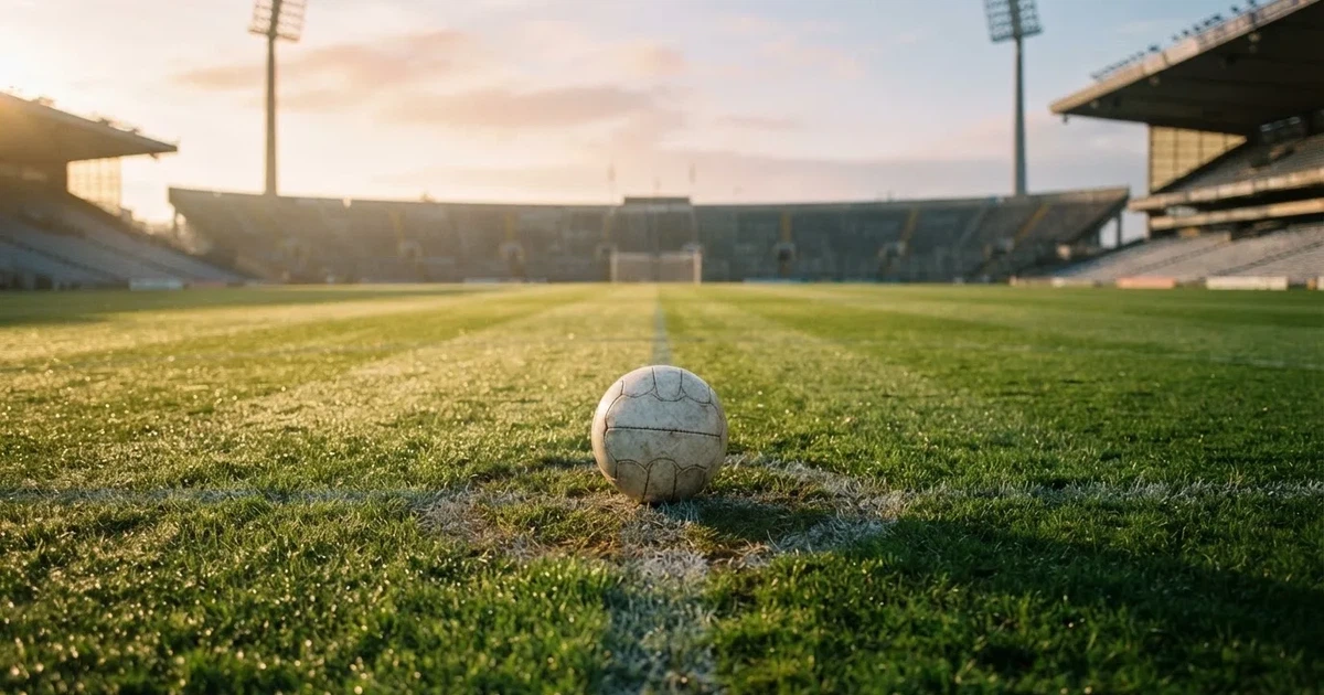 Een voetbal op de middenstip van een grasveld in het ochtendlicht