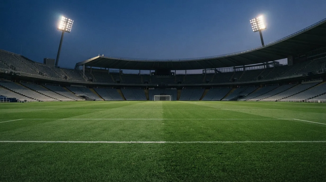 Een leeg voetbalstadion met lichtmasten bij schemering