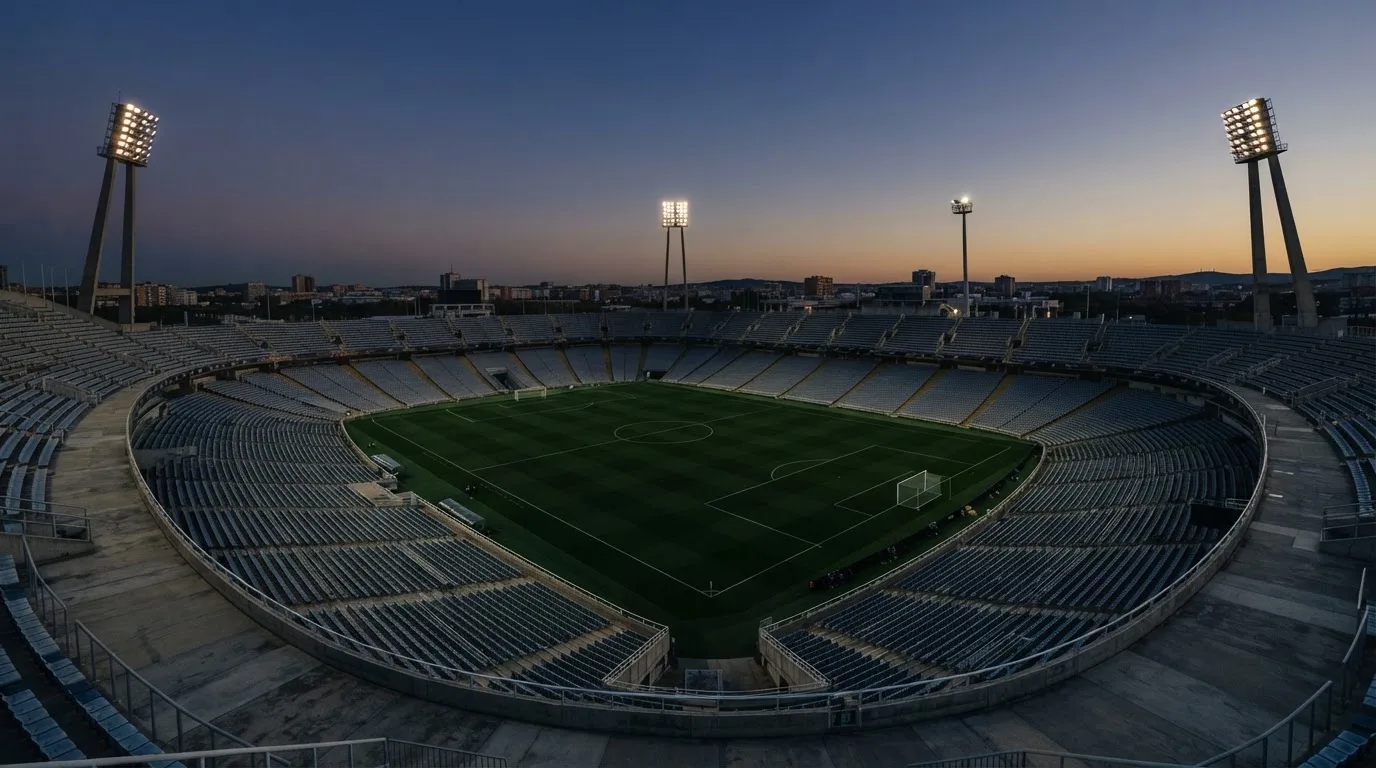 Een leeg voetbalstadion met lichtmasten bij schemering