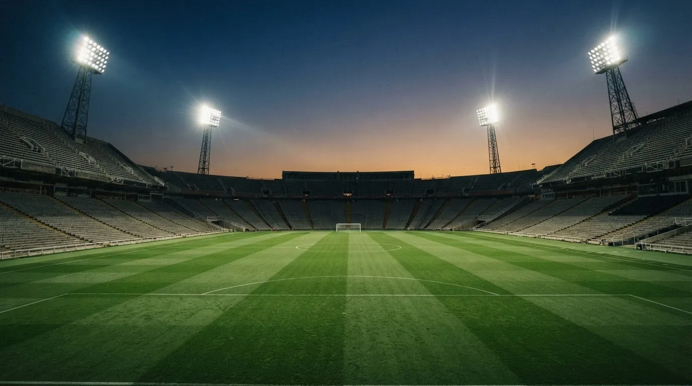 Een leeg voetbalstadion met lichtmasten bij schemering